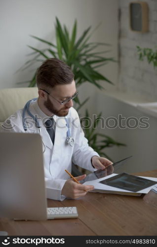 Thoughtful doctor holding chest and lungs xray in medical office