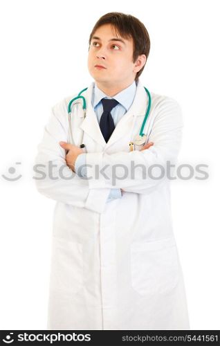 Thoughtful doctor with crossed arms on chest looking up at copy space isolated on white&#xA;