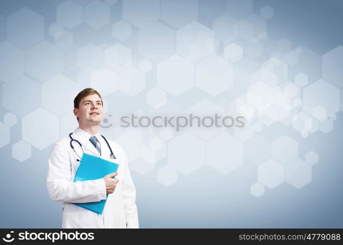 Thoughtful doctor. Young man doctor holding folder thinking something over