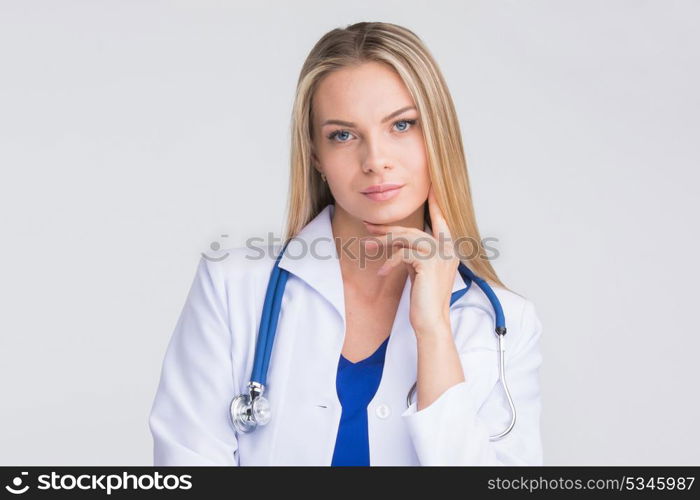 Thoughtful female doctor. Close-up portrait of a beautiful thoughtful female doctor on gray background