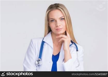 Thoughtful female doctor. Close-up portrait of a beautiful thoughtful female doctor on gray background