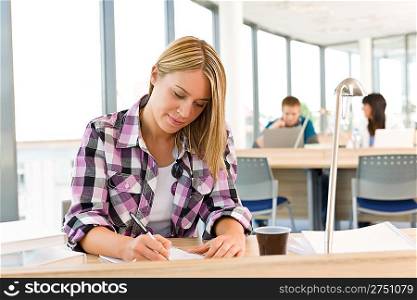 Thoughtful female student in classroom, classmates in background