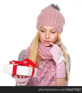 Thoughtful girl in winter clothes looking on christmas present box