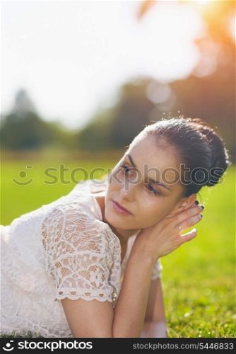 Thoughtful girl laying on grass