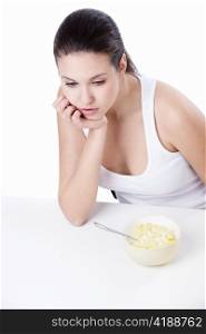 Thoughtful girl with a bowl of corn flakes on a white background