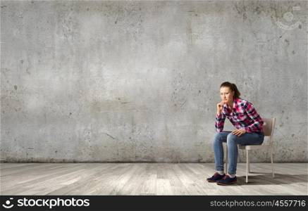 Thoughtful girl. Young thoughtful woman in casual sitting in chair
