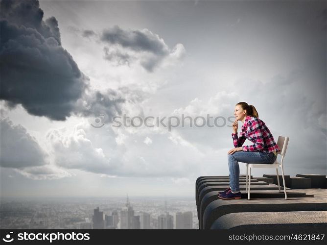 Thoughtful girl. Young thoughtful woman in casual sitting in chair