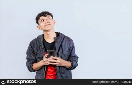 thoughtful guy with cell phone in hand, handsome latin guy thinking with cell phone in hand