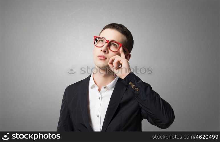 Thoughtful handsome guy. Young man in red glasses and jacket looking thoughtfully up
