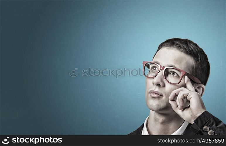 Thoughtful handsome guy. Young man in red glasses and jacket looking thoughtfully up