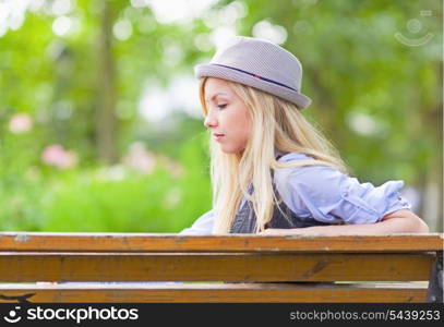 Thoughtful hipster girl sitting on bench in the park
