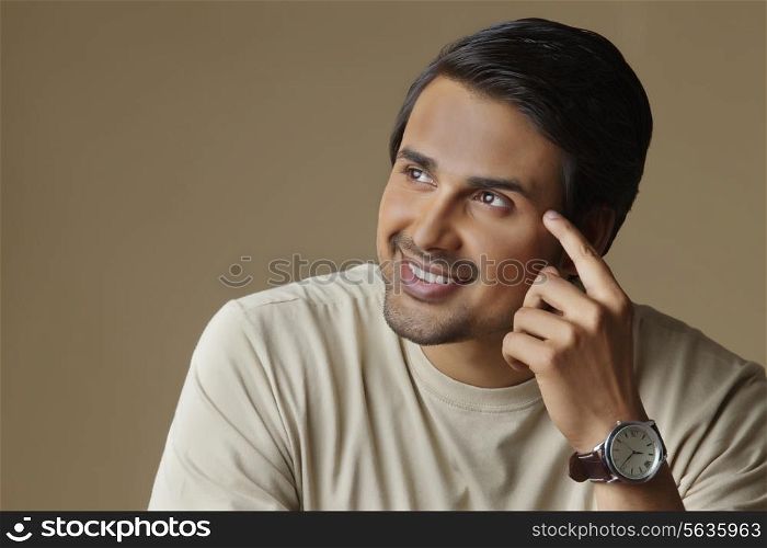 Thoughtful Indian man looking at copy space over colored background