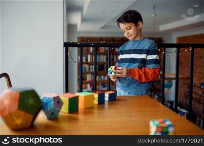 Thoughtful little boy play with puzzle cubes. Toy for brain and logical mind training, creative game, solving of complex problems. Thoughtful little boy play with puzzle cubes