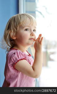 thoughtful little girl is by window portrait