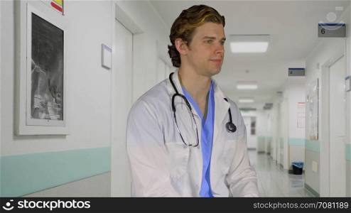 Thoughtful looking doctor turns to camera outside exam room