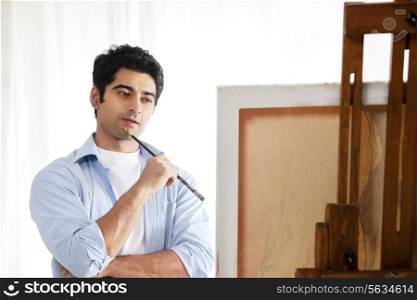 Thoughtful male painter standing in front of easel
