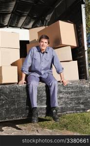Thoughtful man sitting in the truck with pile of boxes behind him