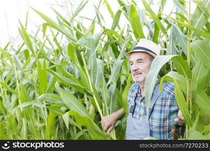 Thoughtful man standing against plants at farm