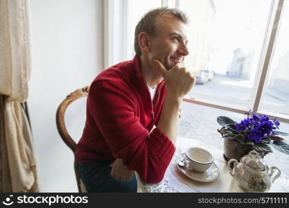 Thoughtful mid adult man sitting at table in cafe