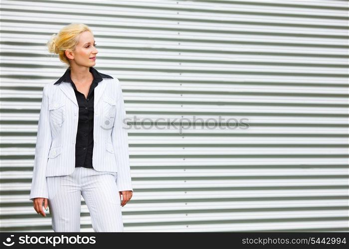 Thoughtful modern business woman standing at office building and looking at copyspace &#xA;