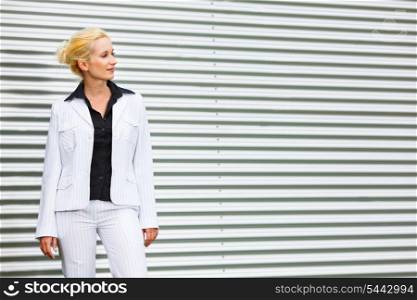 Thoughtful modern business woman standing at office building and looking at copyspace &#xA;