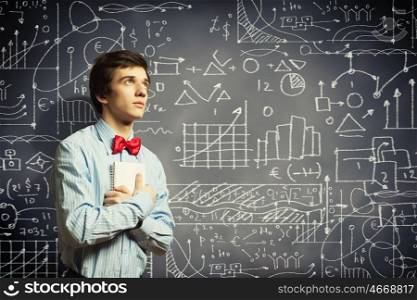 Thoughtful student with notebook. Image of thoughtful male student holding notebook in classroom
