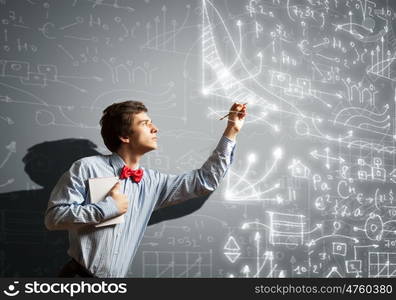 Thoughtful student with notebook. Image of thoughtful male student holding notebook in classroom