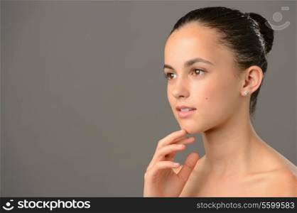 Thoughtful teenage girl beauty skin care looking away gray background
