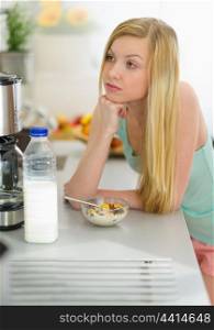 Thoughtful teenager girl having breakfast in kitchen