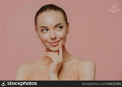 Thoughtful topless lady with perfect skin, undergoing facial treatments, isolated indoors. Cosmetology and wellness concept.