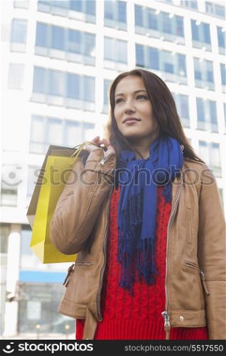Thoughtful woman carrying shopping bags in winter