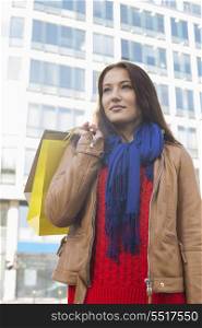 Thoughtful woman carrying shopping bags in winter