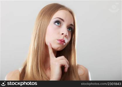 Thoughtful woman face. Attractive blonde long hair girl thinking making decision on gray background