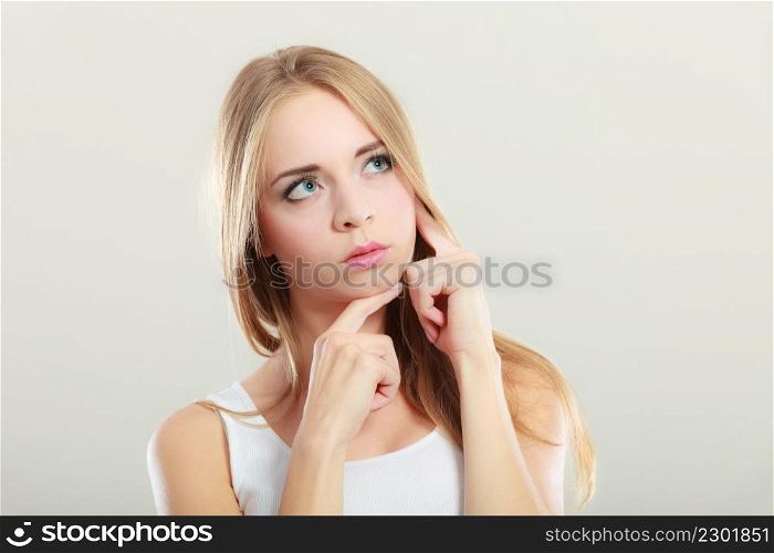 Thoughtful woman face. Attractive blonde long hair girl thinking making decision on gray background