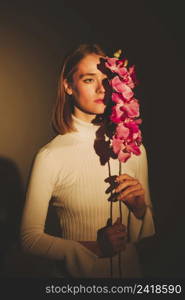 thoughtful woman holding pink flower