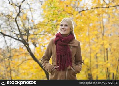 Thoughtful woman in jacket looking away at park during autumn