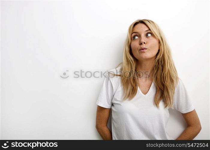 Thoughtful woman puckering against white background