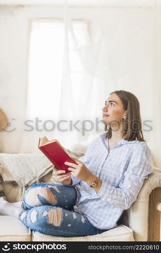 thoughtful woman reading book sofa