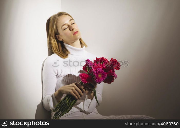 thoughtful woman sitting with pink flowers bouquet