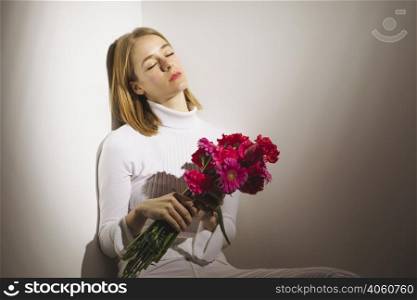 thoughtful woman sitting with pink flowers bouquet