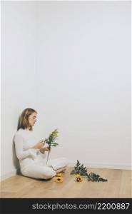 thoughtful woman sitting with plant branches