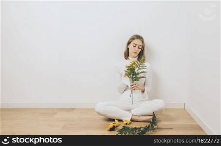 thoughtful woman sitting with plant branches floor