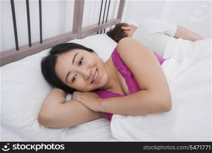 Thoughtful woman smiling while man sleeping in bed