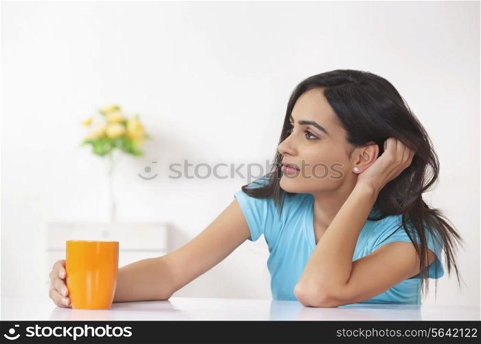 Thoughtful woman with coffee cup at home