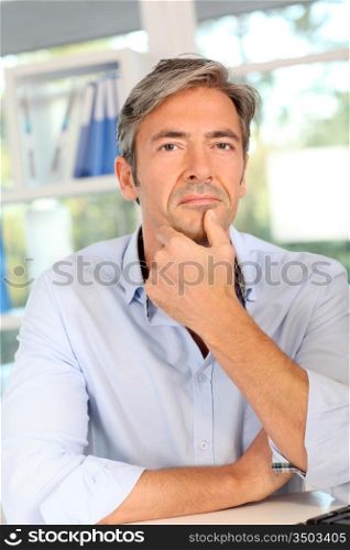 Thoughtful worker in office with hand on chin