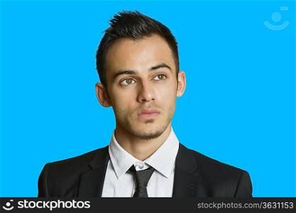 Thoughtful young businessman looking away over colored background
