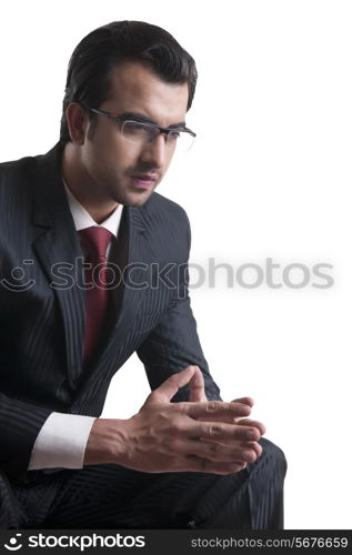 Thoughtful young businessman sitting over white background