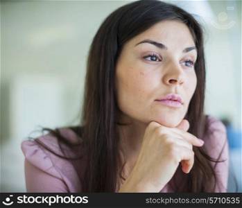 Thoughtful young businesswoman looking away in office