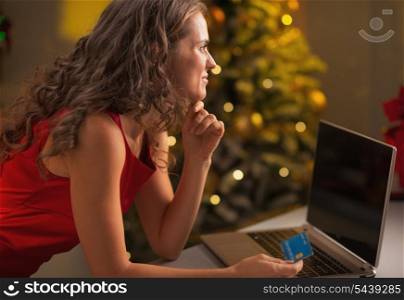 Thoughtful young housewife with credit card making online christmas purchases