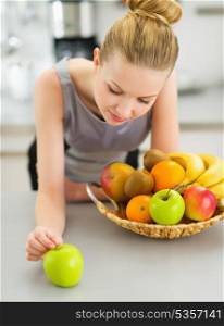 Thoughtful young housewife with plate of fruits